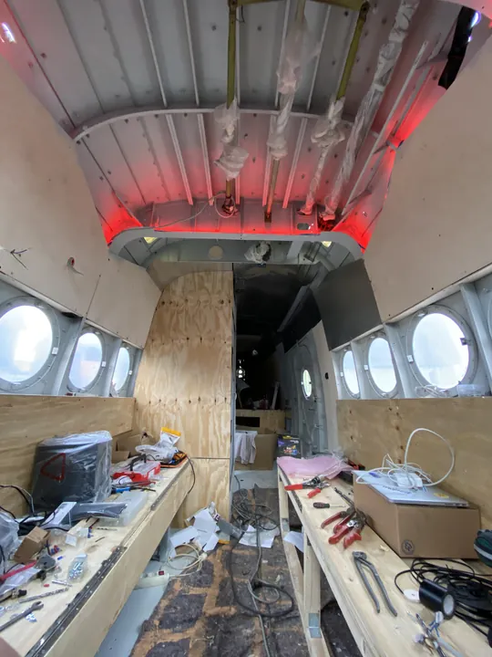 Innenausbau zwischen Kabeln, Werkzeug und Flugzeugfenstern.