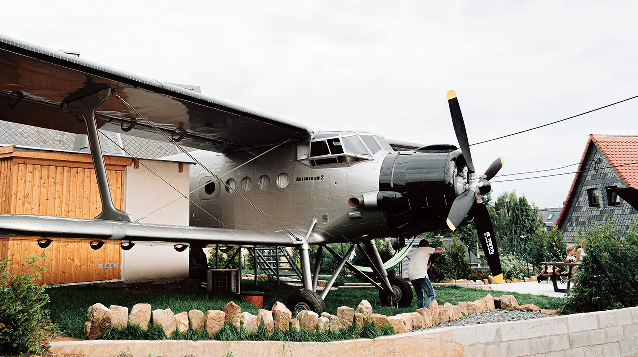 Die Antonov An-2 im Garten mit Terrasse unter den Tragflächen